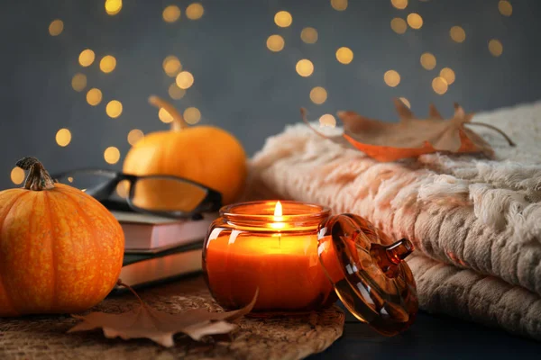 Mavi ahşap masada yanan mum ile sonbahar kompozisyonu bulanık ışıklara karşı, yakın çekim