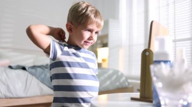 Küçük çocuk saçını evde tarıyor.