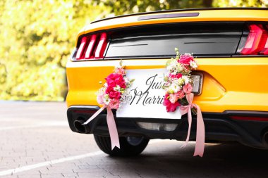 Düğün arabası. Cabriolet dekore edilmiş. Sadece evlilik kartı ve açık havada güzel çiçekler, yakın plan.