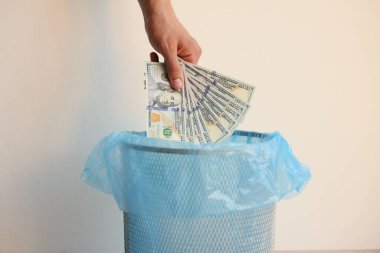 Beyaz arka planda çöp kutusuna dolar atan adam, yakın plan.