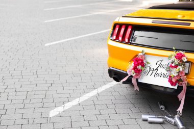 Düğün arabası. Cabriolet, Yeni Evli kartıyla dekore edilmiş, güzel çiçekler ve teneke kutular, yakın plan. Metin için boşluk