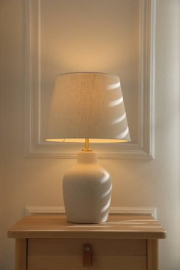 Stylish lamp on nightstand near white wall indoors
