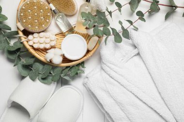 Flat lay composition with bathrobe and spa essentials on white wooden background