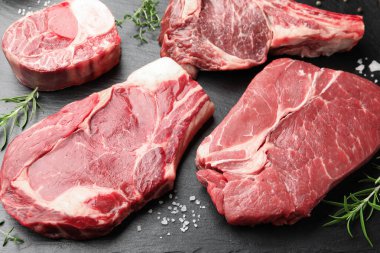 Siyah masanın üstünde çiğ et ve baharat parçaları.