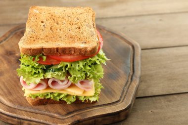 Jambonlu, peynirli ve sebzeli lezzetli sandviç, ahşap masa, yakın plan. Metin için boşluk