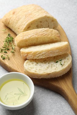Taze ciabatta, bitkiler ve yağ gri masada, yakın plan.