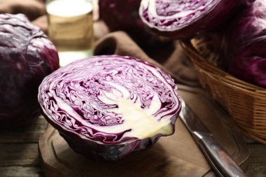Fresh ripe red cabbages and knife on wooden table, closeup