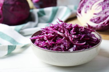 Whole and cut fresh red cabbages on white wooden table, closeup