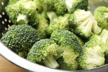 Fresh raw broccoli in colander on table, closeup