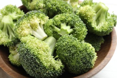 Fresh green broccoli in bowl on white table, closeup