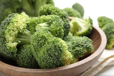 Fresh green broccoli in bowl on white table, closeup