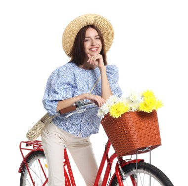 Beyaz arka planda çiçek sepeti olan şapkalı ve bisikletli gülümseyen kadın.