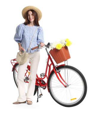 Beyaz arka planda çiçek sepeti olan şapkalı ve bisikletli gülümseyen kadın.