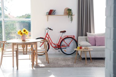 Odasında sandalye, kanepe ve bisiklet olan ahşap yemek masası.