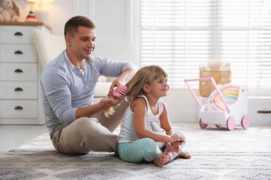 Baba evde kızının saçını tarıyor, mesaj atmak için yer açıyor.