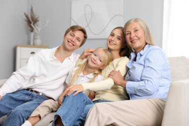 Oğlunun ailesiyle birlikte evdeki kanepede oturan yaşlı kadın.