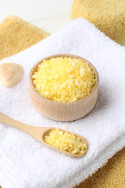 Yellow sea salt, towels, seashell and sponge on table, closeup