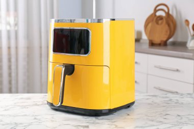 Mutfaktaki beyaz mermer masada bir fritöz var.