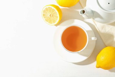 Aromatik çay bardakta, limon ve çaydanlık beyaz masada, düz yerde. Metin için boşluk