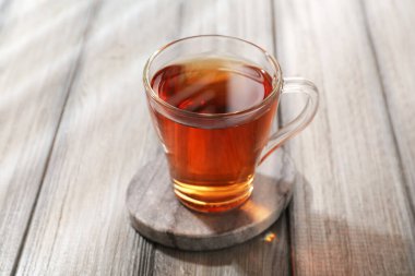Aromatic black tea in glass cup on wooden table, closeup