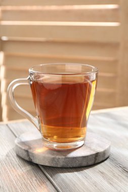Aromatic black tea in glass cup on wooden table, closeup