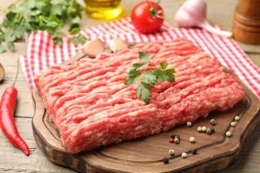 Maydanozlu çiğ et ve ahşap masada baharatlar, yakın plan.