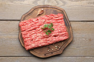 Maydanozlu çiğ et ve ahşap masada baharatlar.