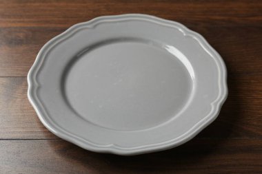 Empty ceramic plate on wooden table, closeup