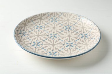 Empty ceramic plate on white wooden table, closeup