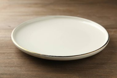 Clean ceramic plate on wooden table, closeup
