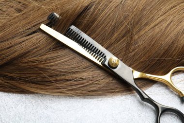 Açık arkaplanda güzel saç teli ve makas, yakın plan.