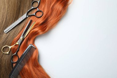 Farklı renklerde güzel saç telleri ve beyaz arka planda kuaför aletleri, düz yatış. Metin için boşluk