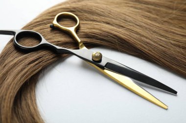 Beyaz arka planda güzel saç teli ve makas, yakın plan.