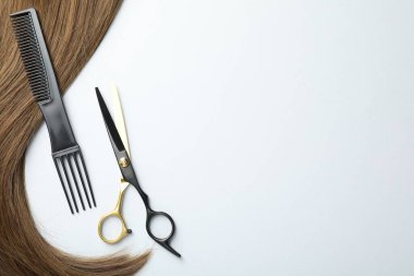 Güzel saç teli ve beyaz arka planda kuaför aletleri, düz yatış. Metin için boşluk
