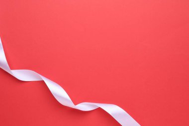 Beautiful white ribbon on red background, top view. Space for text