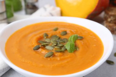 Çekirdekli balkabağı çorbası ve fesleğen masada, yakın plan.