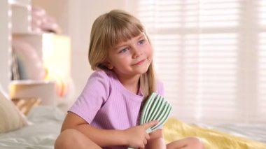 Evde saçını tarayan küçük bir kız.