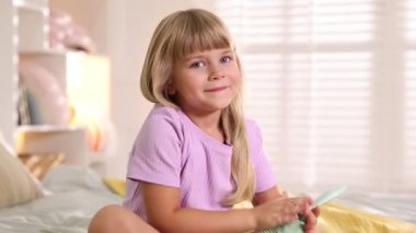 Evde yatakta fırçayla gezen küçük kız.