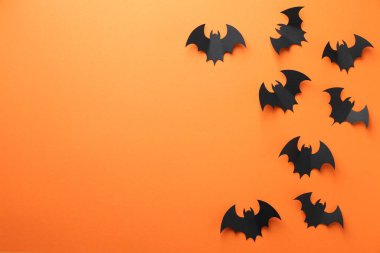 Cadılar Bayramı dekoru. Siyah kağıt yarasalar turuncu arka planda, düz yerde. Metin için boşluk