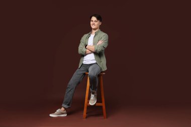 Kahverengi arka planda, kotlu şık bir adam.