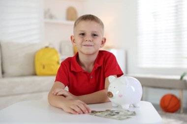 Cep harçlığı ve kumbarası olan küçük bir çocuk.