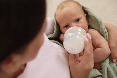 Anne yeni doğmuş bebeğini biberonla besliyor.