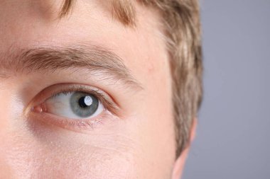 Açık gri arka planda güzel gözleri olan adam, yakın plan.