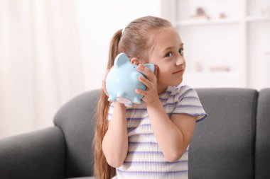 Cep harçlığı. Evdeki kanepede kumbaralı küçük kız.