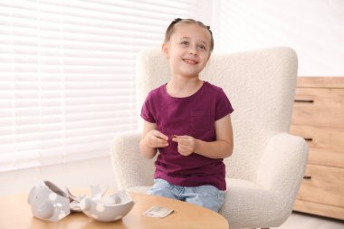 Evdeki koltukta cep harçlığı olan küçük kız, mesaj atmak için yer.