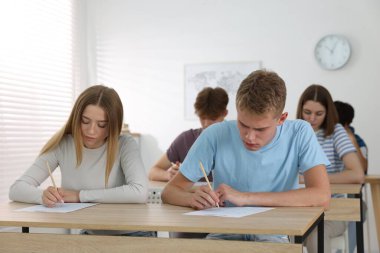Ahşap masada sınava giren öğrenciler