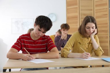 Ahşap masada sınava giren öğrenciler