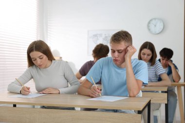 Ahşap masada sınava giren öğrenciler