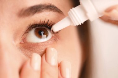 Bulanık arkaplanda göz damlası uygulayan kadın, yakın plan