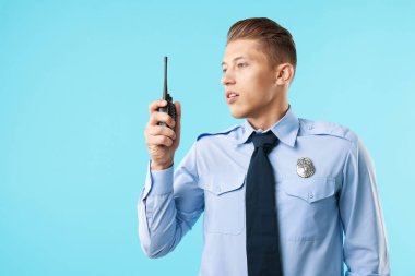 Açık mavi arkaplanda telsizi olan üniformalı genç bir polis memuru, mesaj için yer var.